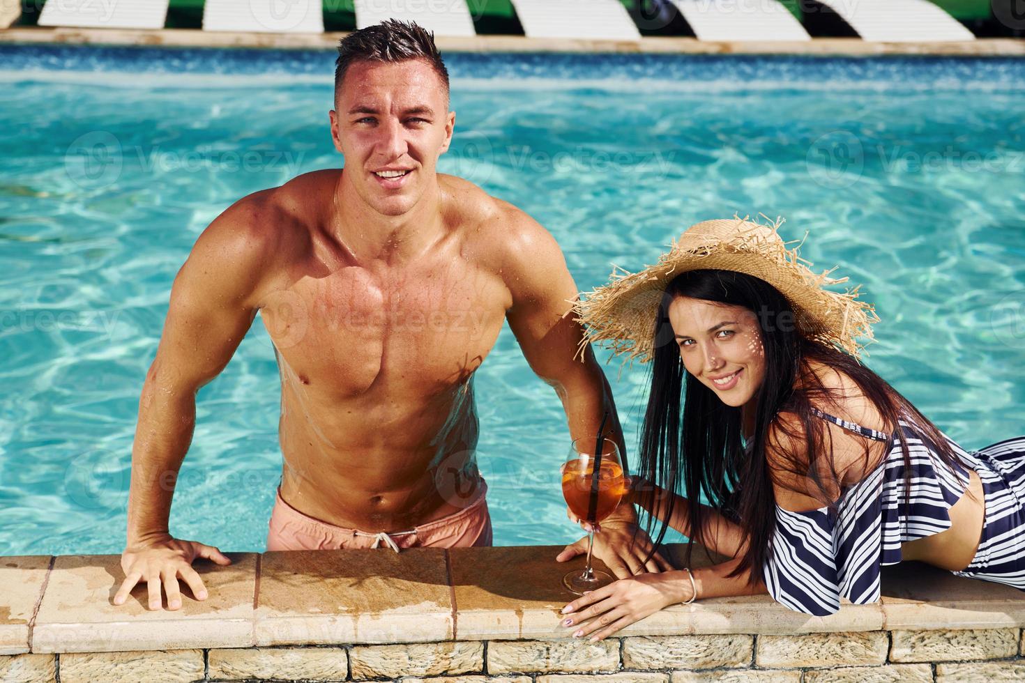 pareja alegre o amigos juntos en la piscina de vacaciones foto