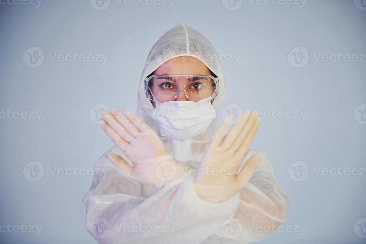 Stop the virus sign. Portrait of female doctor scientist in lab coat, defensive eyewear and mask photo