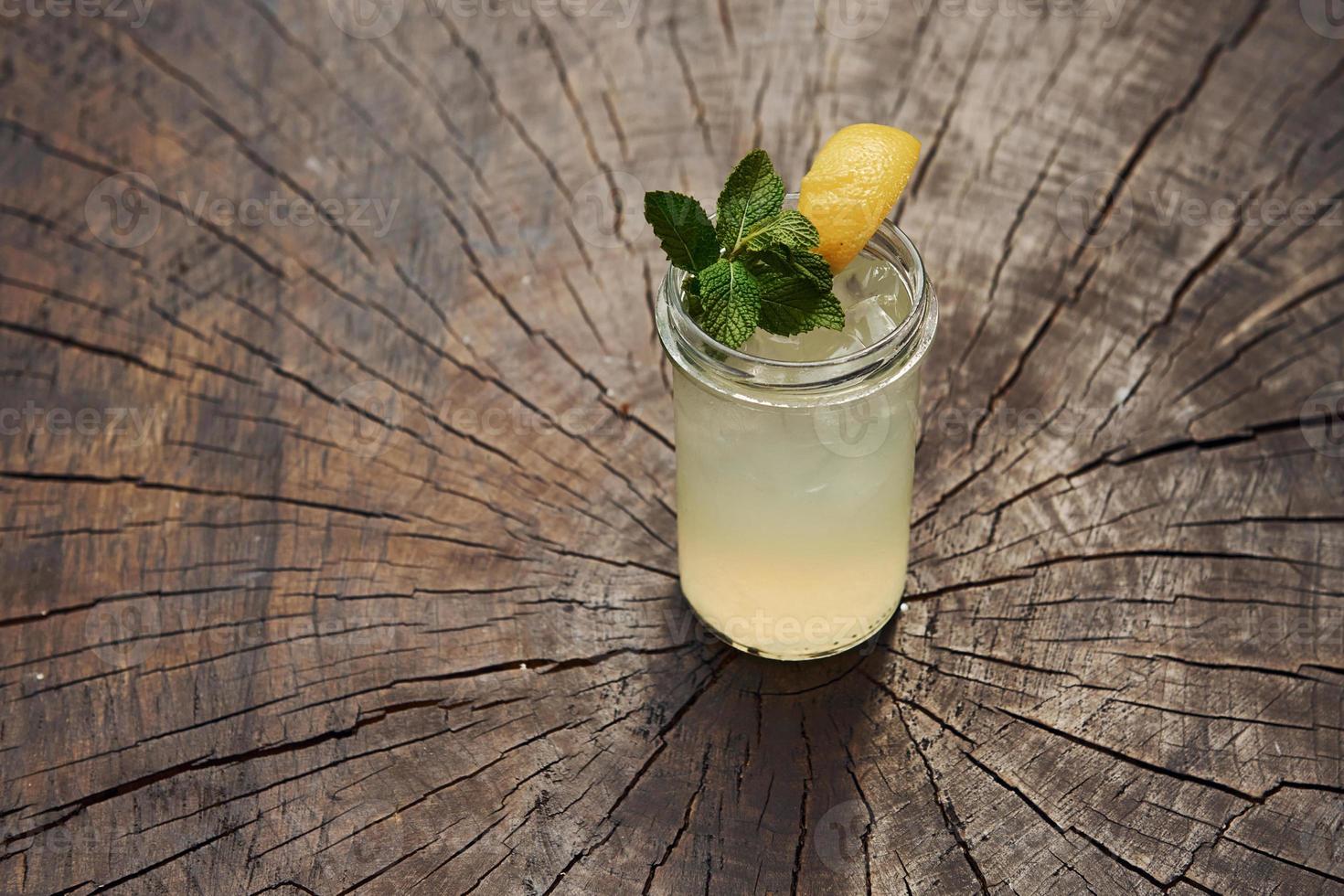 With lemon and mint. Close up view of fresh summer alcoholic cocktail on the wooden table photo