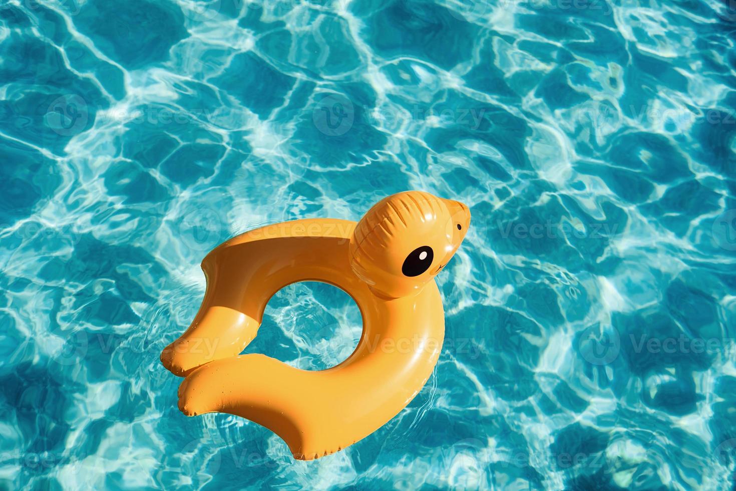 Top view of yellow duck toy for swimming in the pool at daytime photo