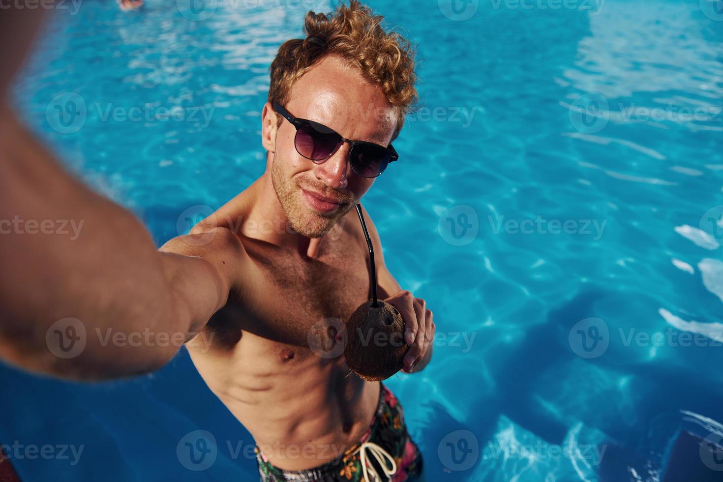 Positive young man have a rest outdoors in swimming pool at daytime photo