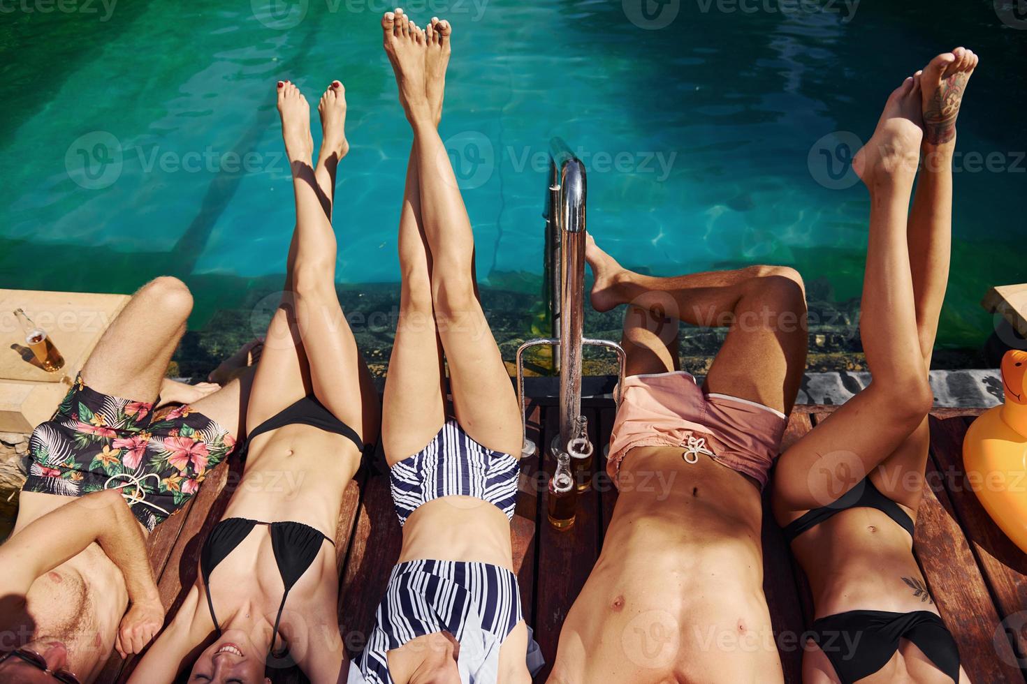 Taking a rest together. Group of young happy people have fun in swimming pool at daytime photo