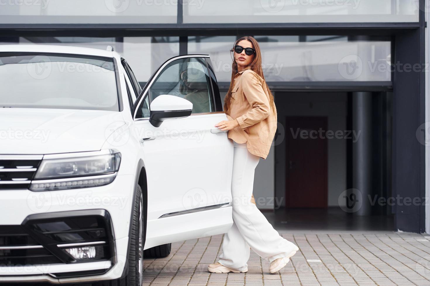 Outside near car. Fashionable beautiful young woman and her modern automobile photo