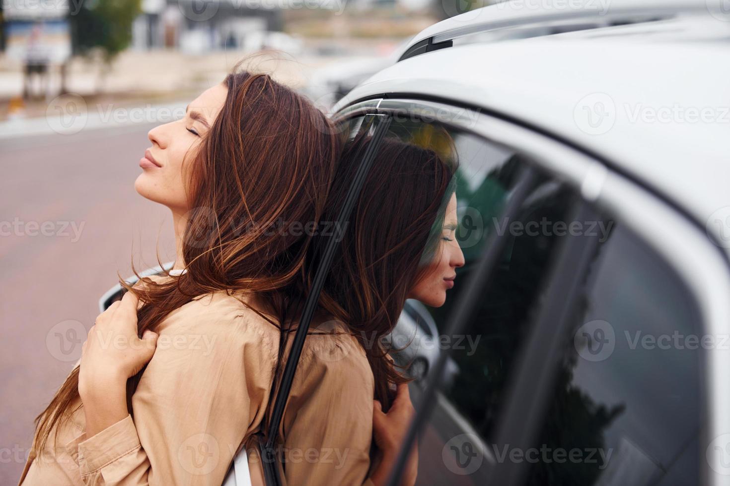se apoya en la puerta. mujer joven hermosa de moda y su automóvil moderno foto
