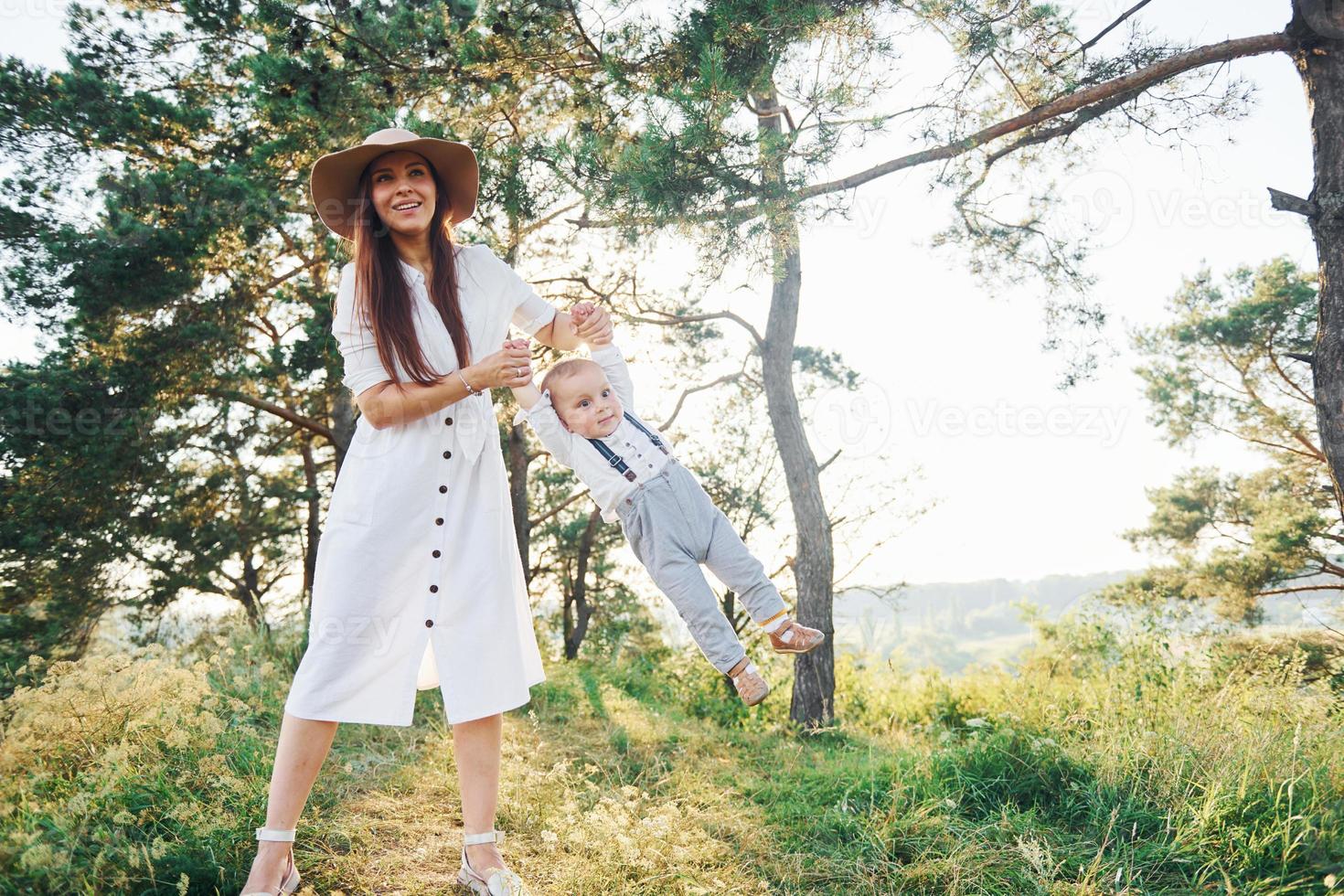 Young mother with her little son is outdoors in the forest. Beautiful sunshine photo