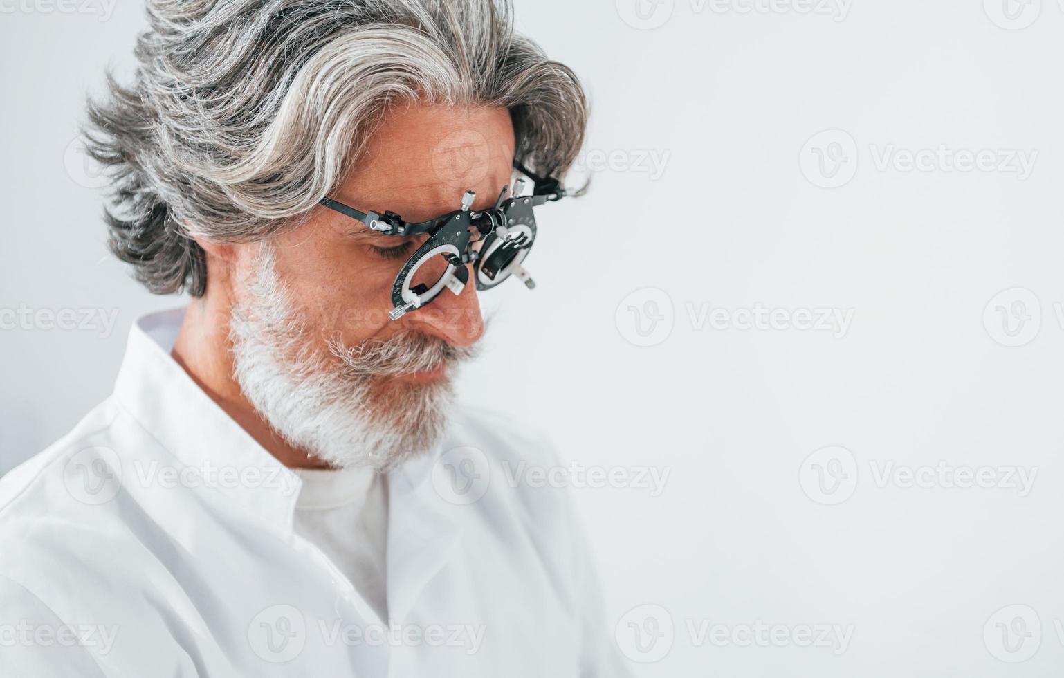 Senior man with grey hair and beard is in ophthalmology clinic photo