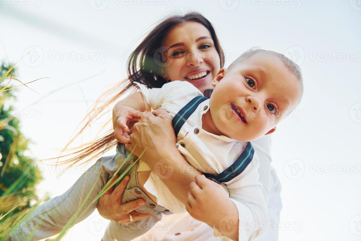 Happy family smiling and having fun. Young mother with her little son is outdoors in the agricultural field. Beautiful sunshine photo