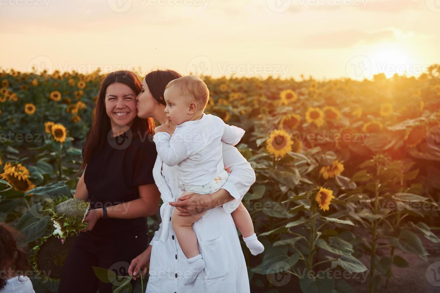 la joven madre con su pequeño hijo, hija y amiga está al aire libre en el campo agrícola. hermoso amanecer foto