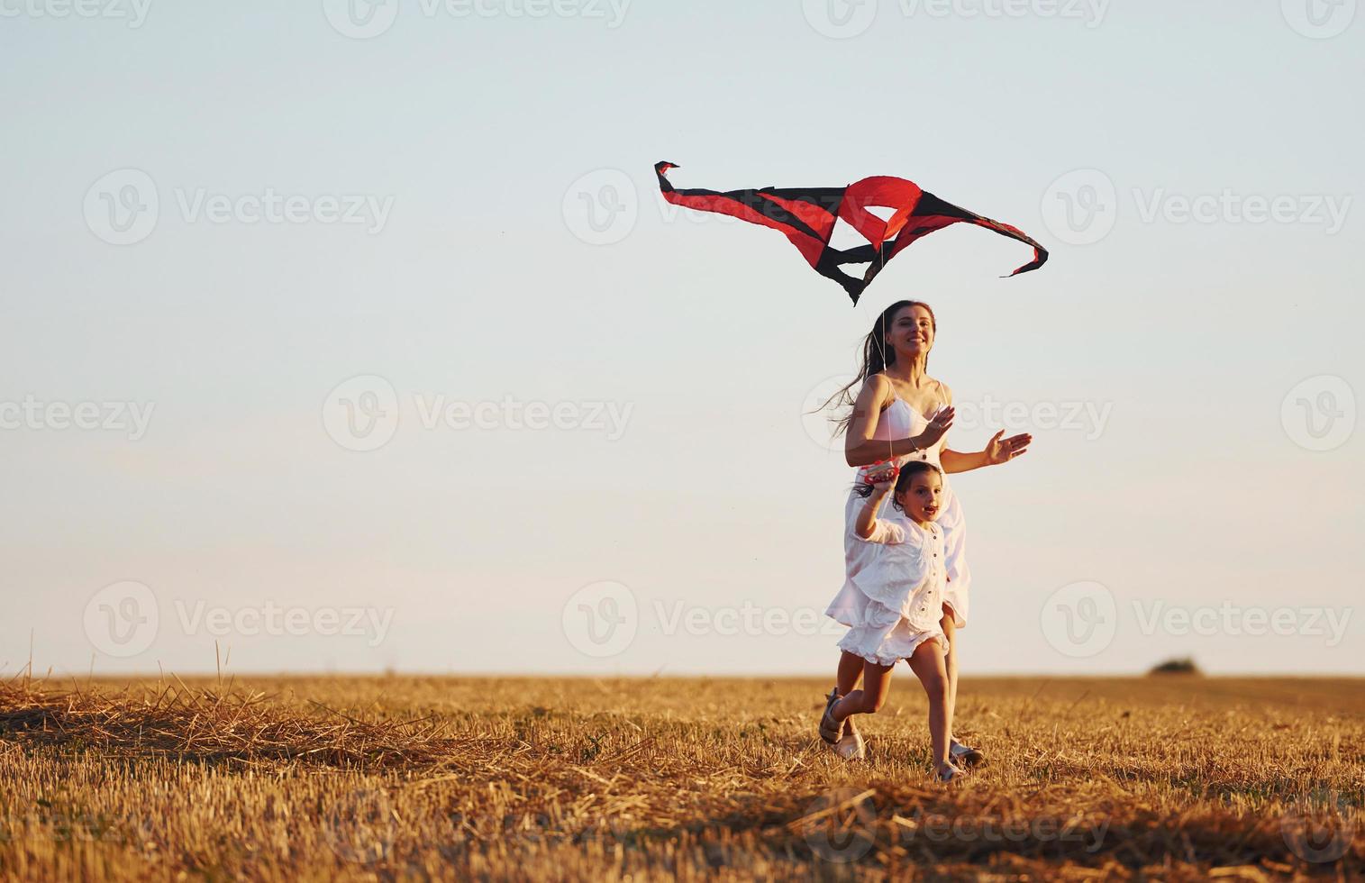 feliz madre con su pequeña hija diviértete jugando con cometas al aire libre en el campo foto