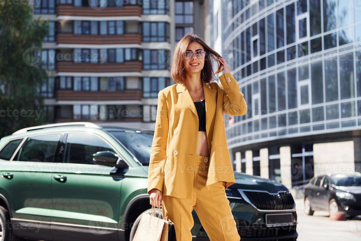 Young fashionable woman in burgundy colored coat at daytime with her car photo