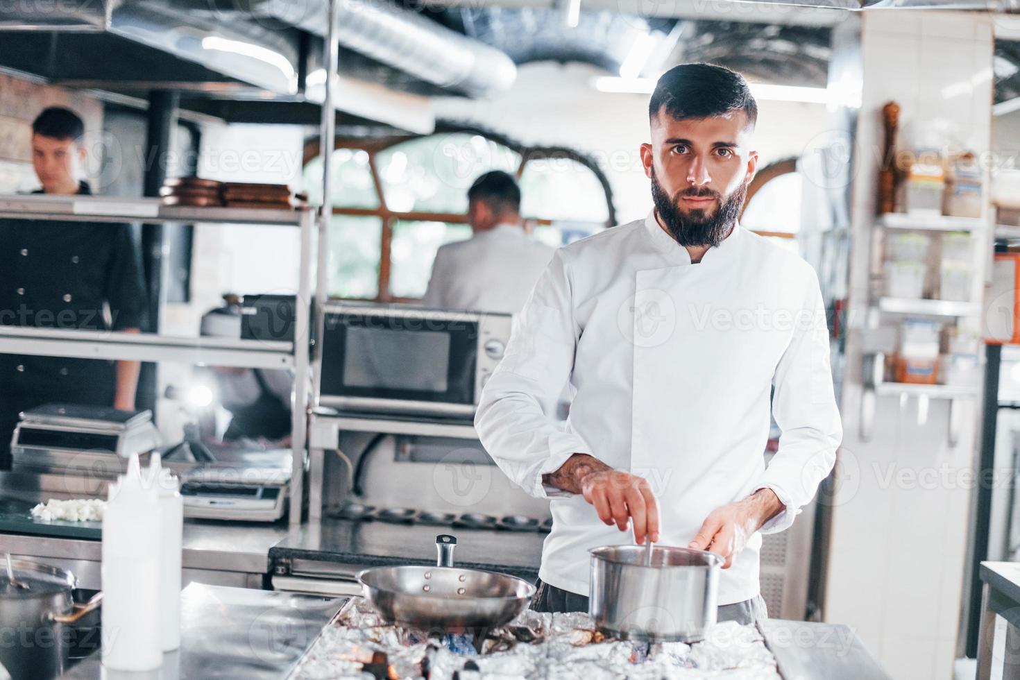 Cooks delicious soup. Chef in white uniform cooking food at kitchen. Busy day at work photo