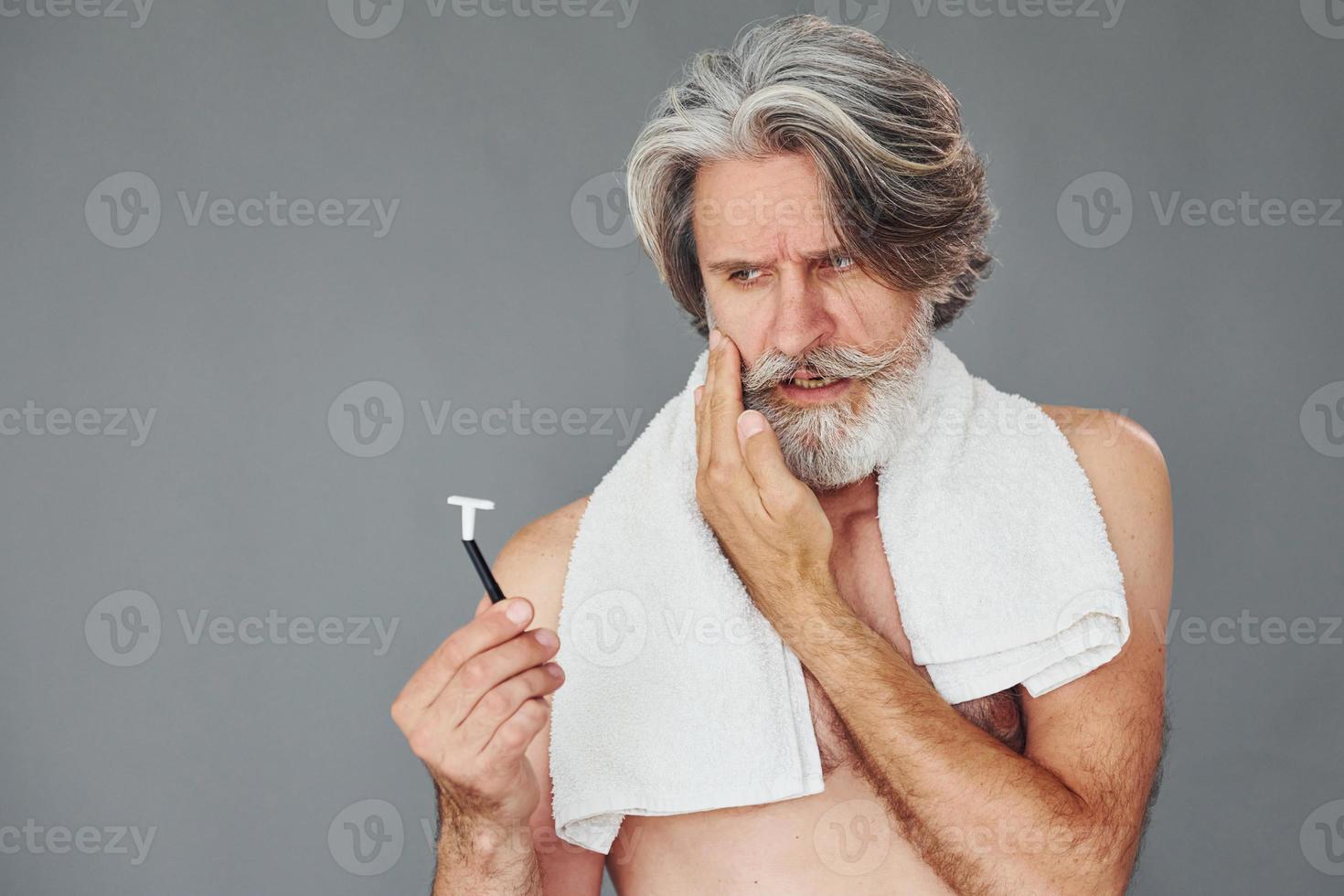 Conception of shaving. Stylish modern senior man with gray hair and beard is indoors photo