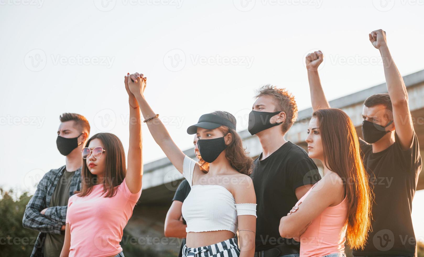 Fists rased high up. Group of protesting young people that standing together. Activist for human rights or against government photo