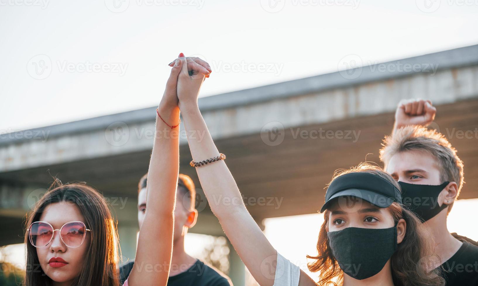 Fists rased high up. Group of protesting young people that standing together. Activist for human rights or against government photo