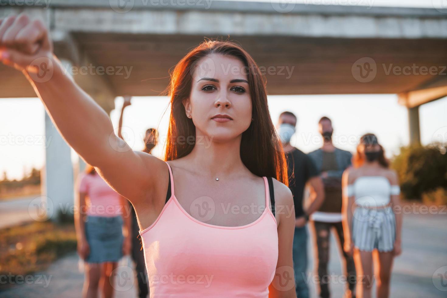 Woman on the front of crowd. Group of protesting young people that standing together. Activist for human rights or against government photo