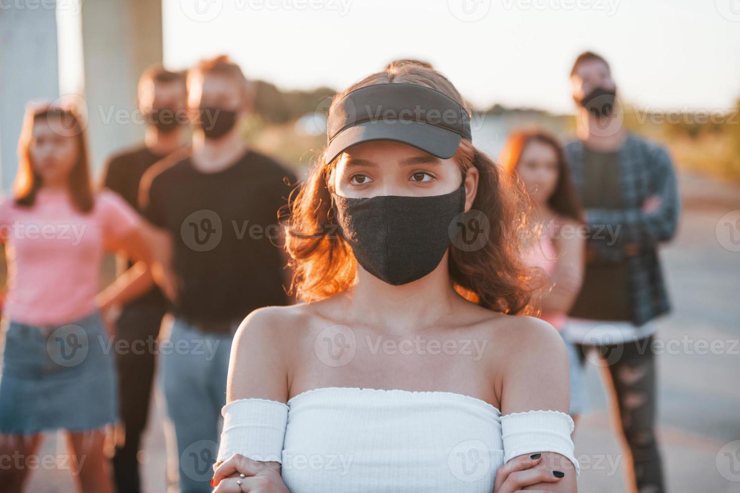 Beautiful girl in mask. Group of protesting young people that standing together. Activist for human rights or against government photo