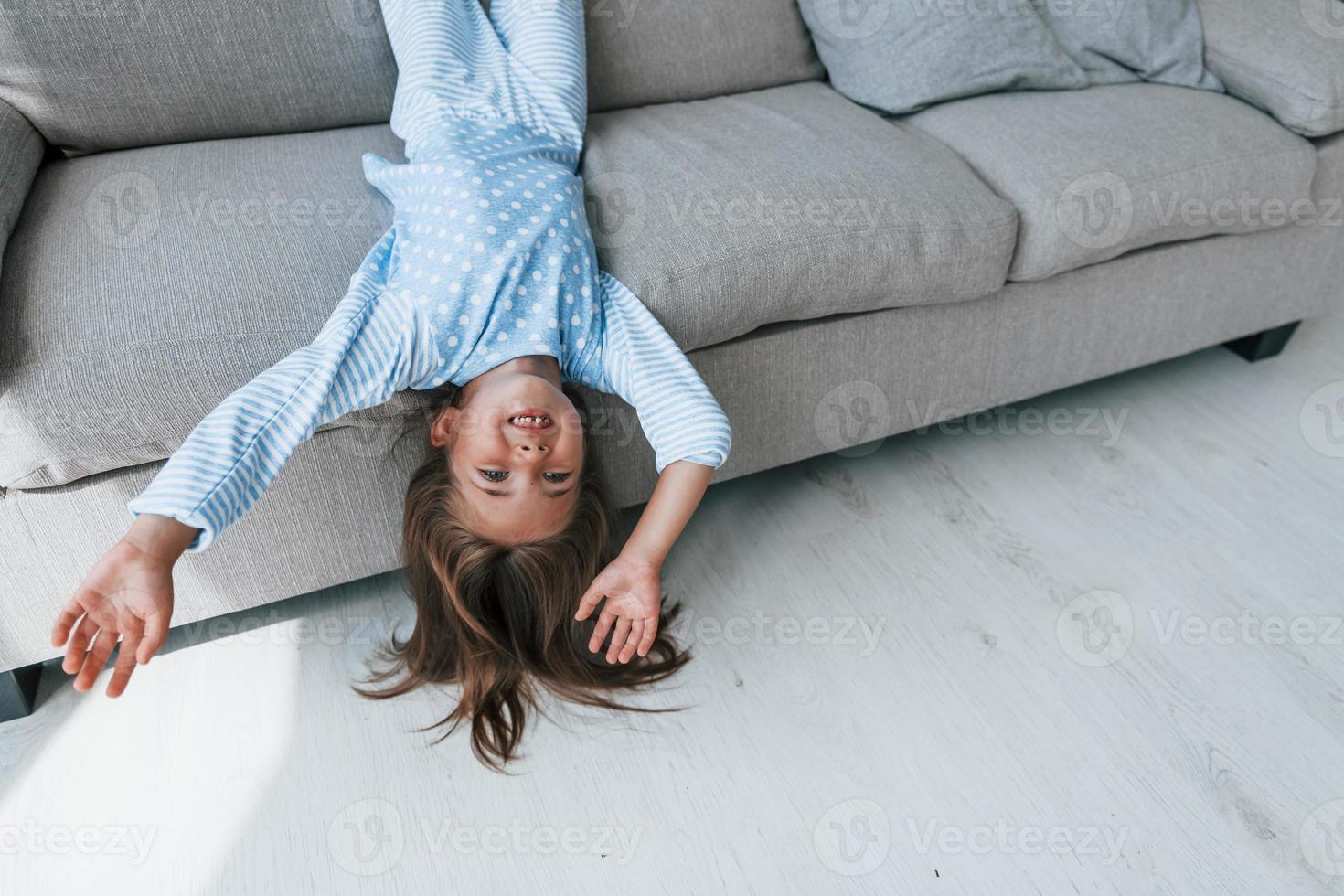 acostado boca abajo en el sofá. linda niña adentro en casa sola. niño disfrutando el fin de semana foto