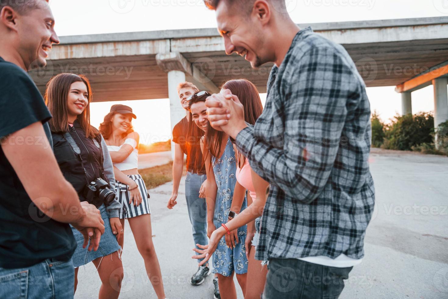 hablando y riendo. grupo de jóvenes amigos alegres divirtiéndose juntos. fiesta al aire libre foto