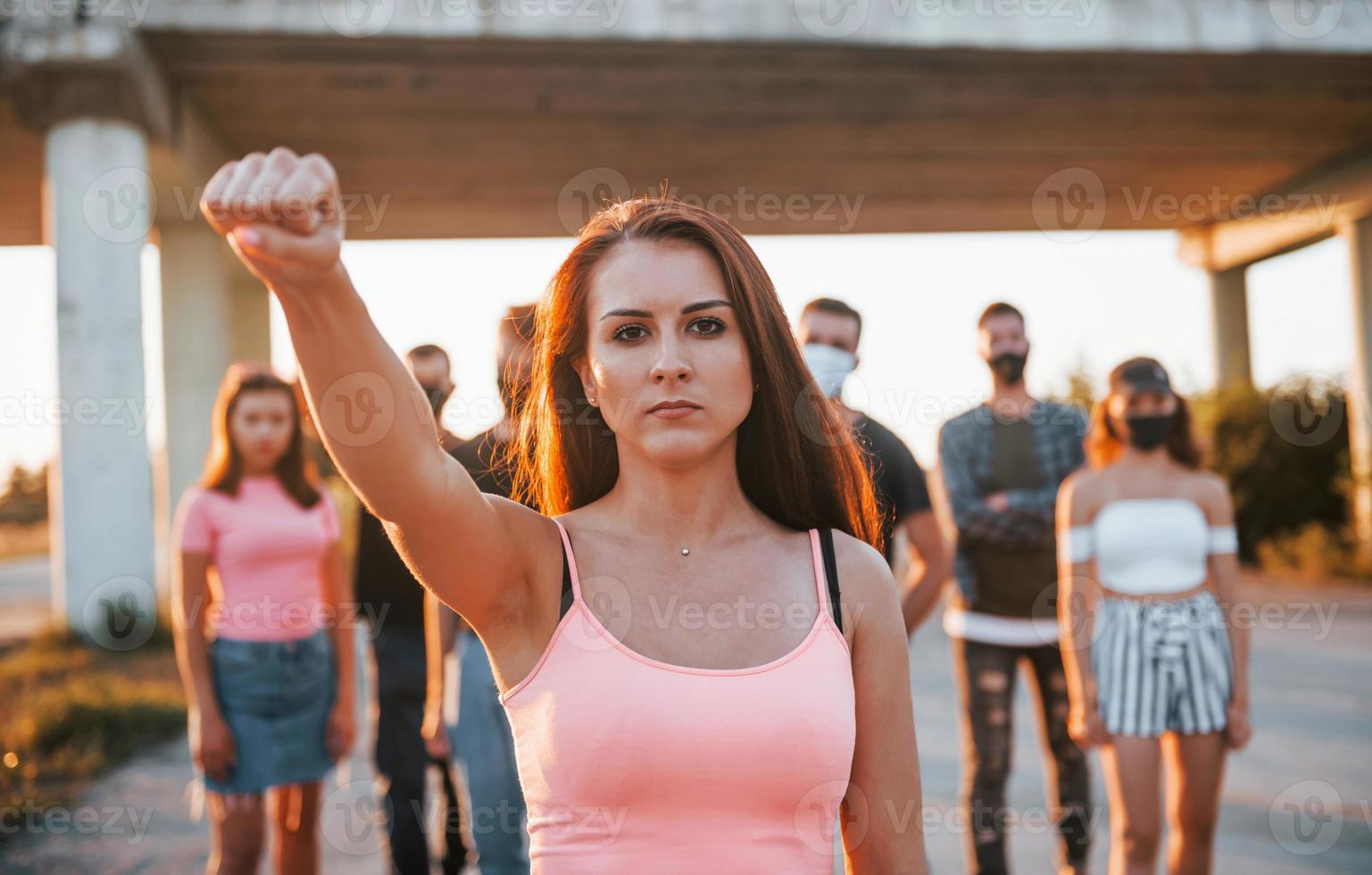 Woman on the front of crowd. Group of protesting young people that standing together. Activist for human rights or against government photo