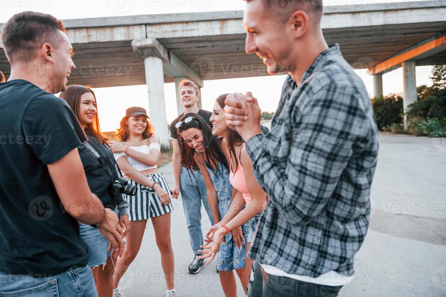 hablando y riendo. grupo de jóvenes amigos alegres divirtiéndose juntos. fiesta al aire libre foto