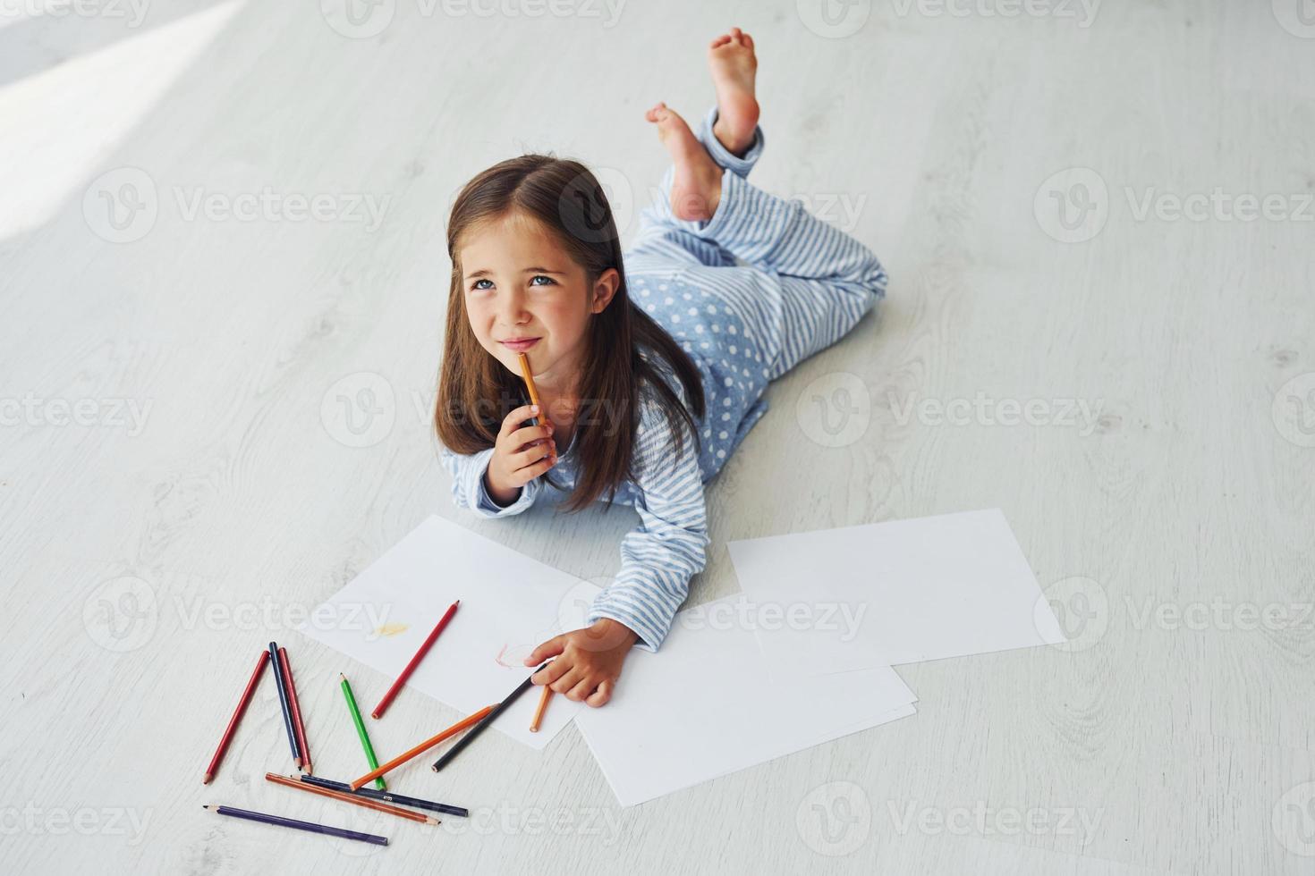 With pencils and paper. Creative cute little girl indoors at home alone. Child enjoying weekend photo