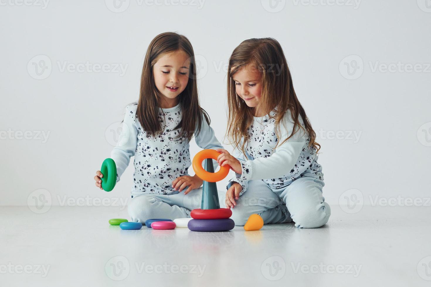 Playing with toy. Two cute little girls indoors at home together. Children having fun photo