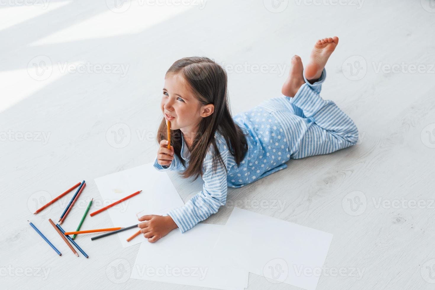 With pencils and paper. Creative cute little girl indoors at home alone. Child enjoying weekend photo