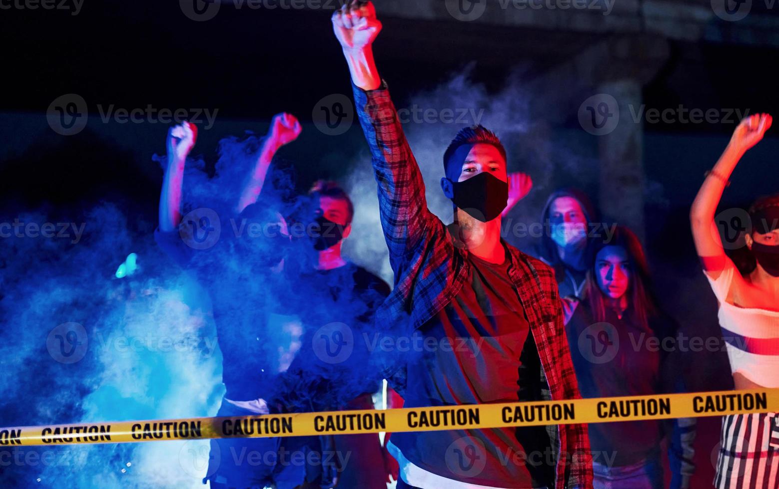 cinta policial de color amarillo. grupo de jóvenes que protestan que se unen. activista por los derechos humanos o contra el gobierno foto