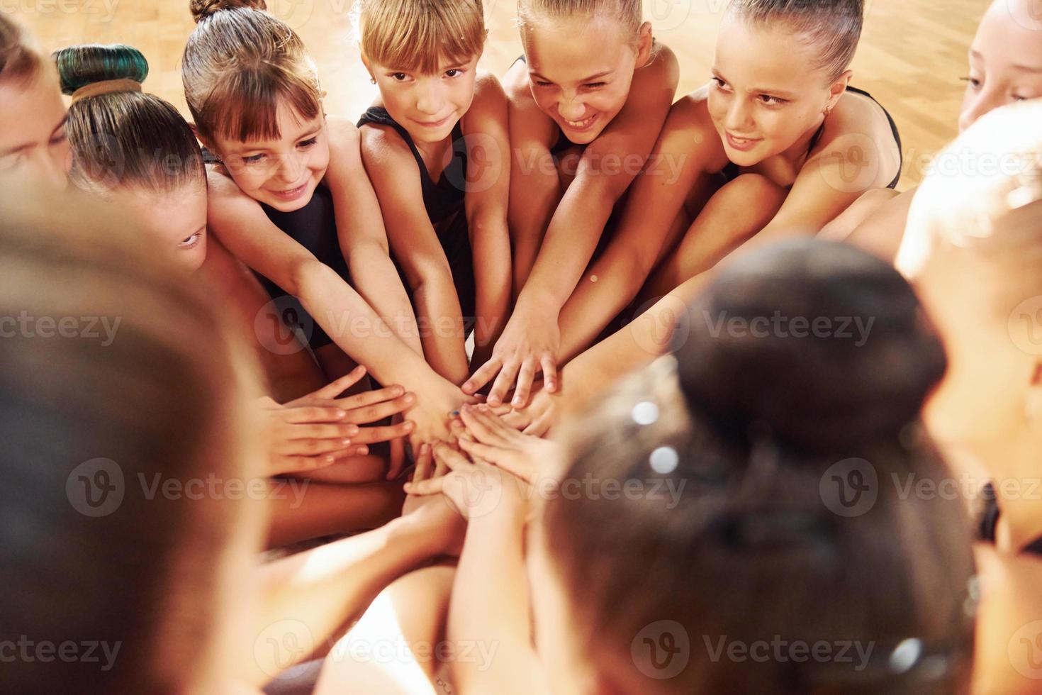 Many of people. Group of female kids practicing athletic exercises together indoors photo