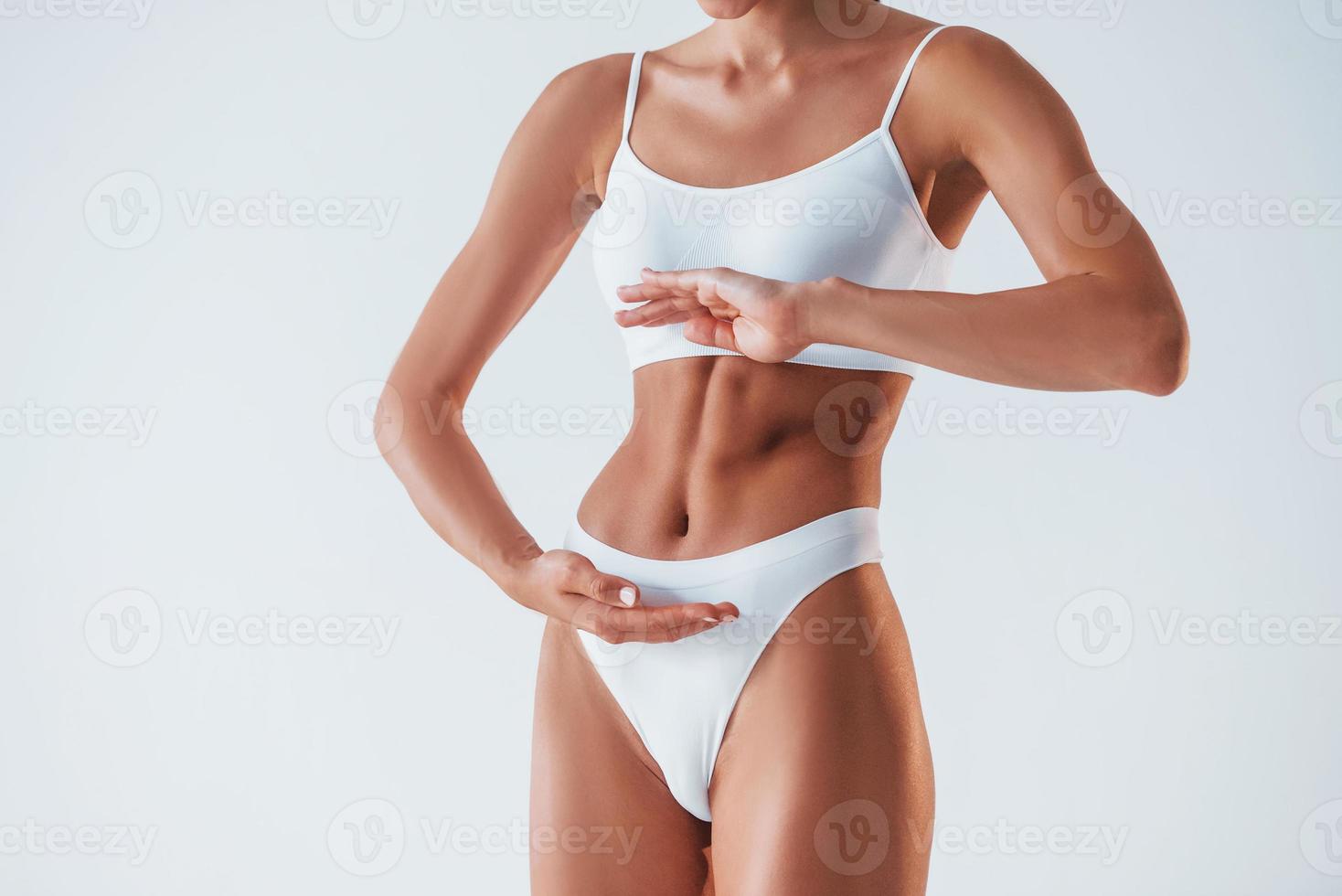 Close up view of stomach. Beautiful woman with slim body in underwear is in the studio photo