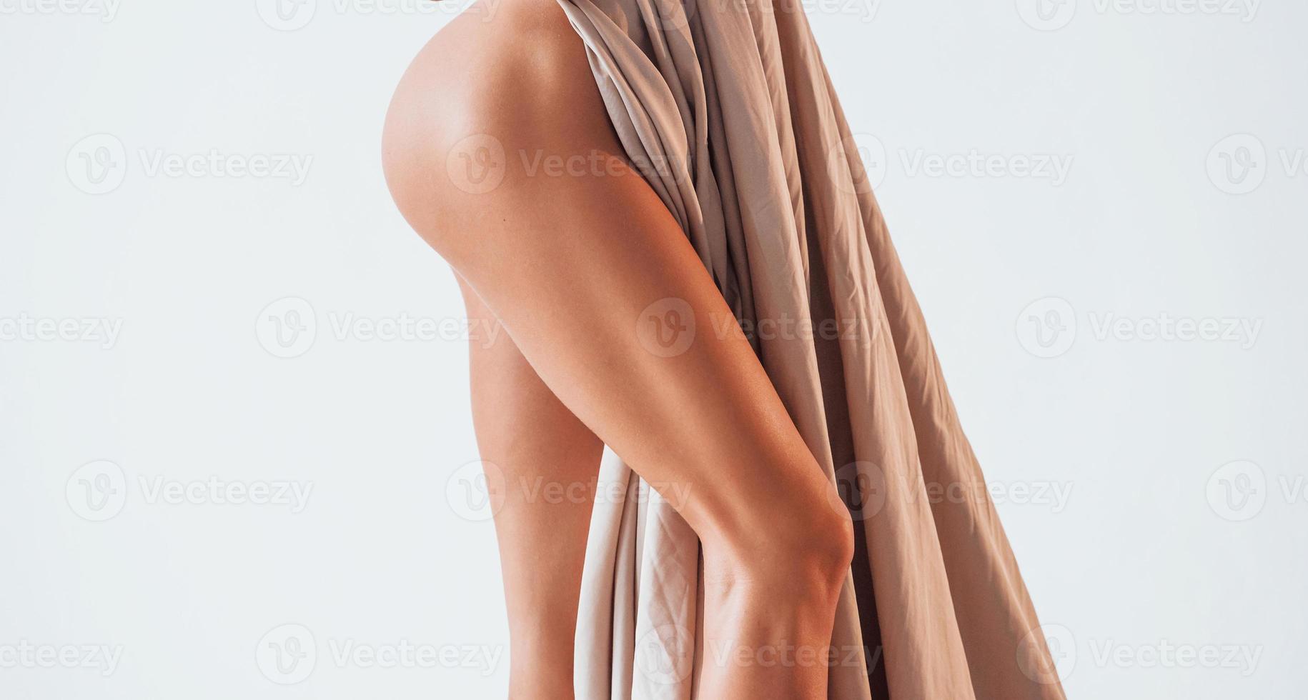 Standing and covering body by cloth. Beautiful woman is in the studio photo