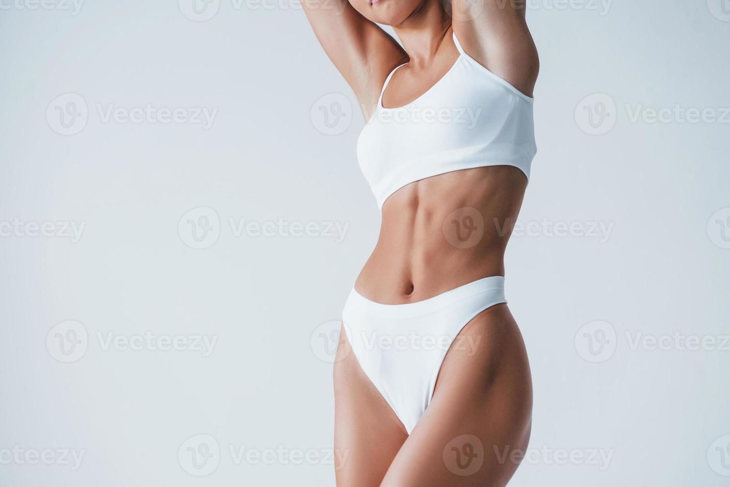 Shows white underwear. Beautiful woman with slim body is in the studio photo