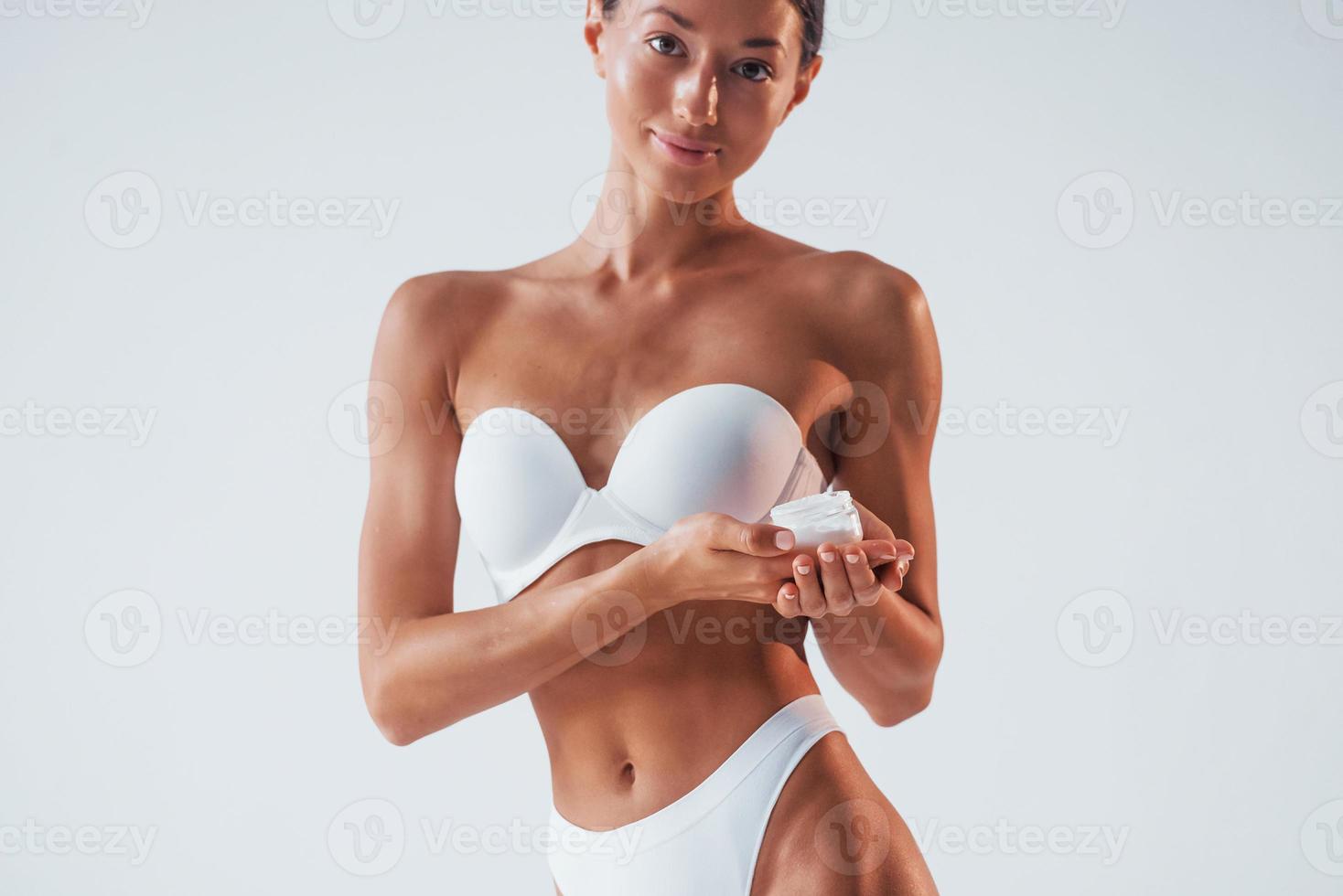 Conception of beauty. Using cream. Woman with slim body in underwear is in the studio photo