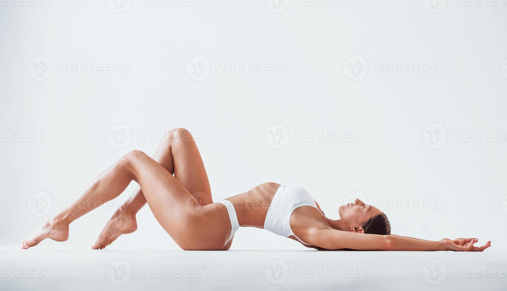Side view of girl that lying down. Beautiful woman with slim body in underwear is in the studio photo