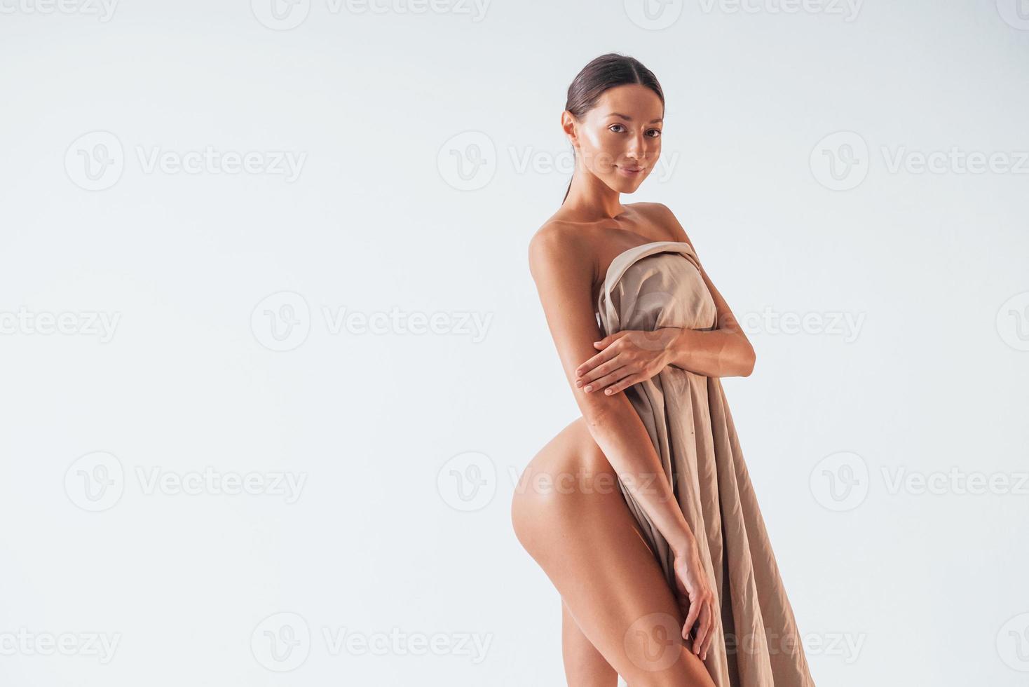 Standing and covering body by cloth. Beautiful woman is in the studio photo