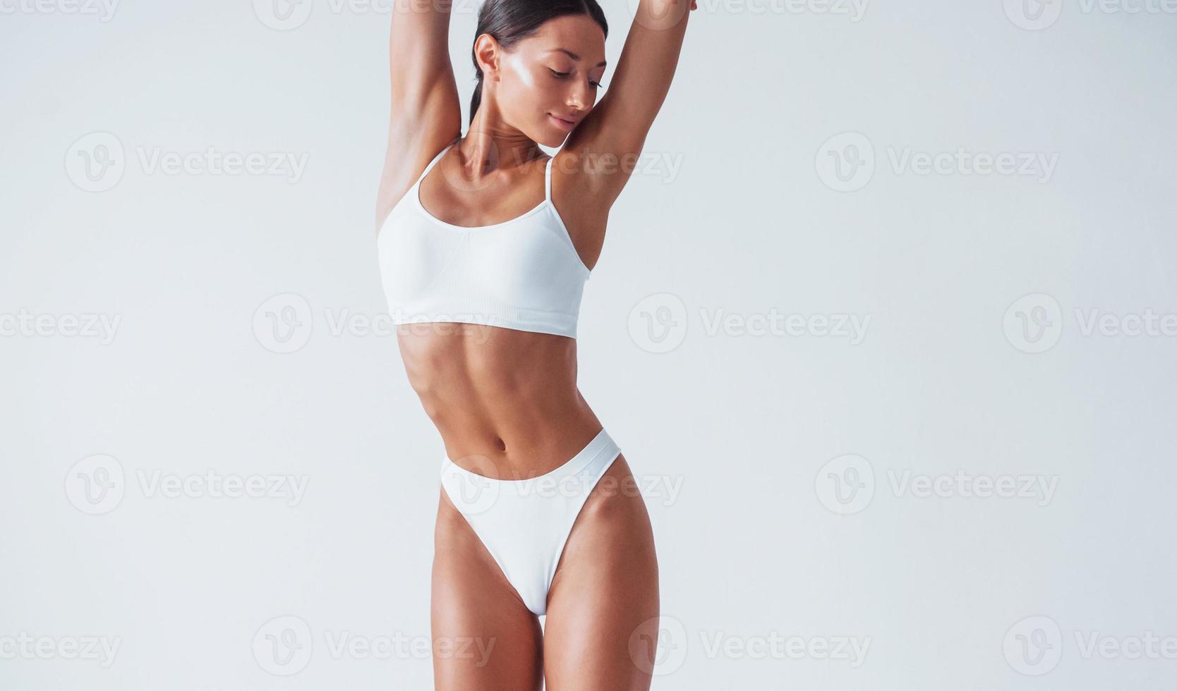 Shows white underwear. Beautiful woman with slim body is in the studio photo