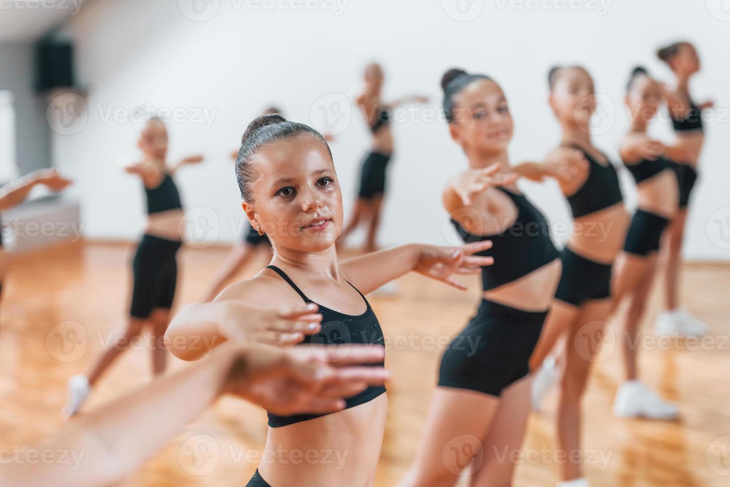 de pie y haciendo movimientos sincronizados. grupo de niñas practicando ejercicios atléticos juntas en el interior foto