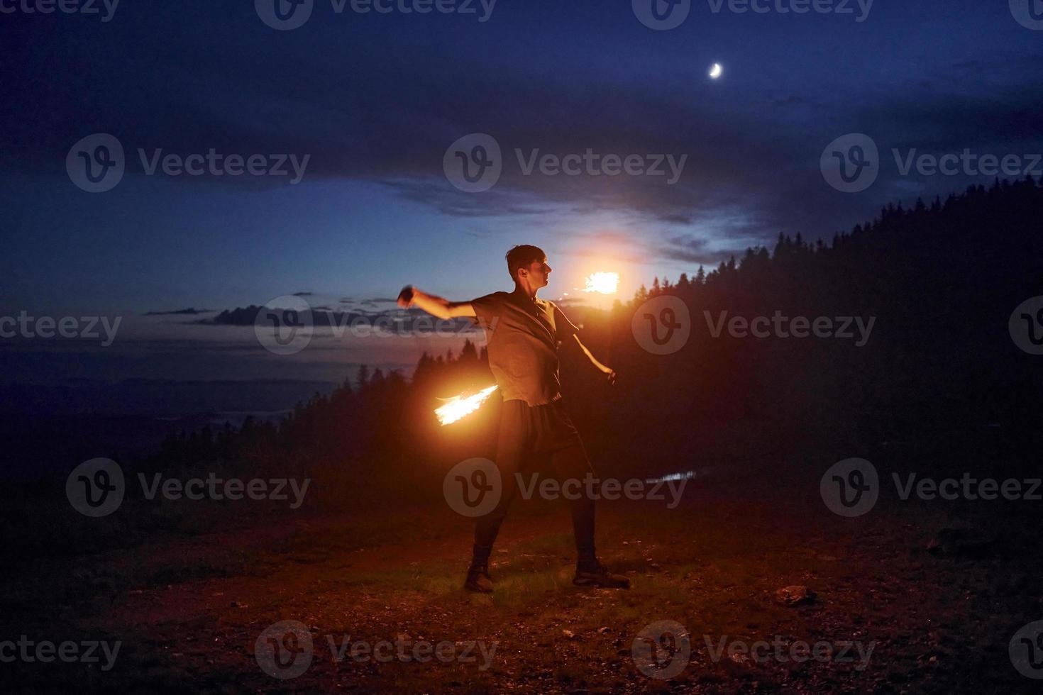 Fire show by man in night Carphatian mountains. Beautiful landscape photo