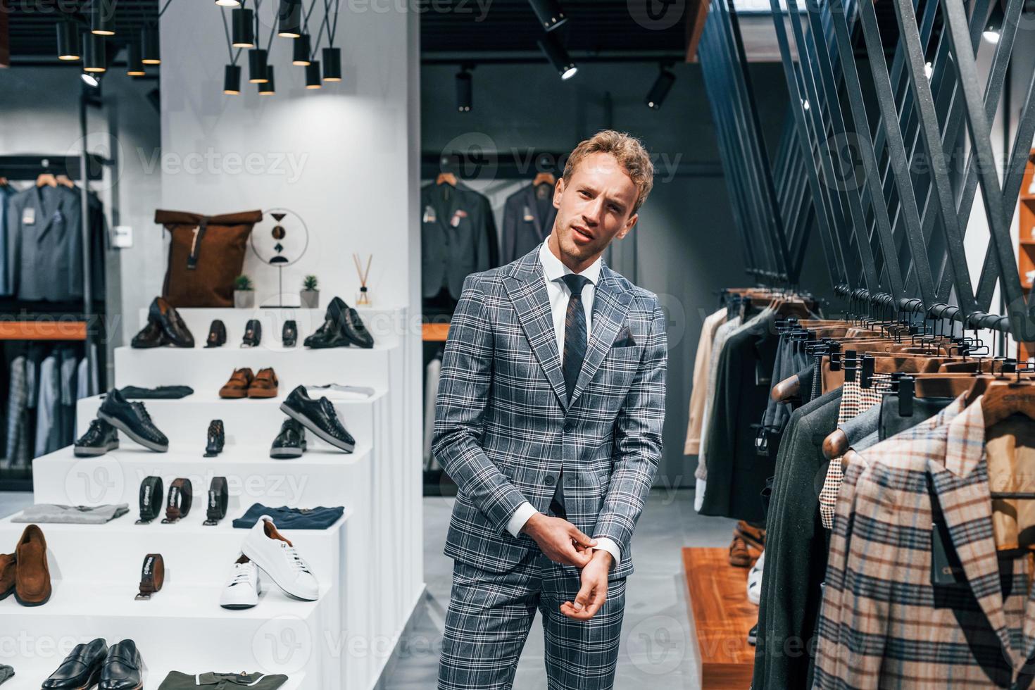 en chaqueta con corbata. chico joven en una tienda moderna con ropa nueva. ropa elegante y cara para hombres foto