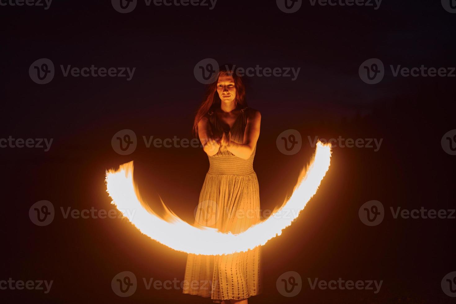 Fire show by woman in dress in night Carphatian mountains. Beautiful landscape photo