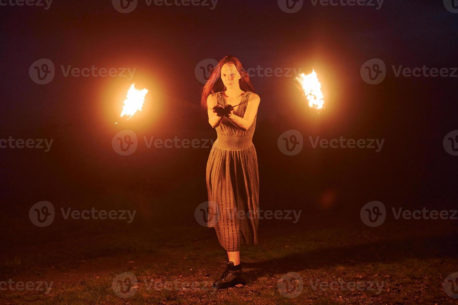 Fire show by woman in dress in night Carphatian mountains. Beautiful landscape photo