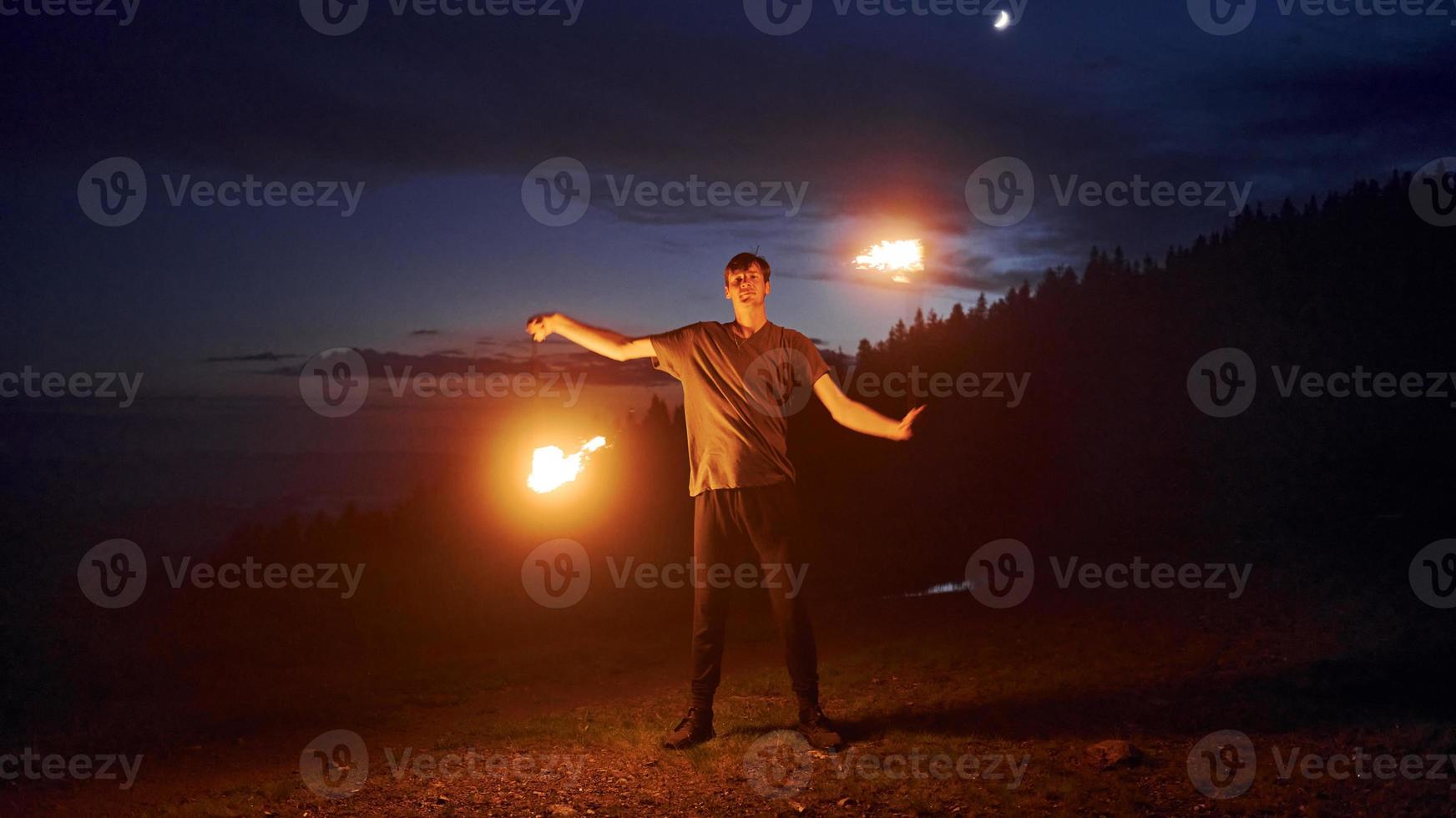 Fire show by man in night Carphatian mountains. Beautiful landscape photo
