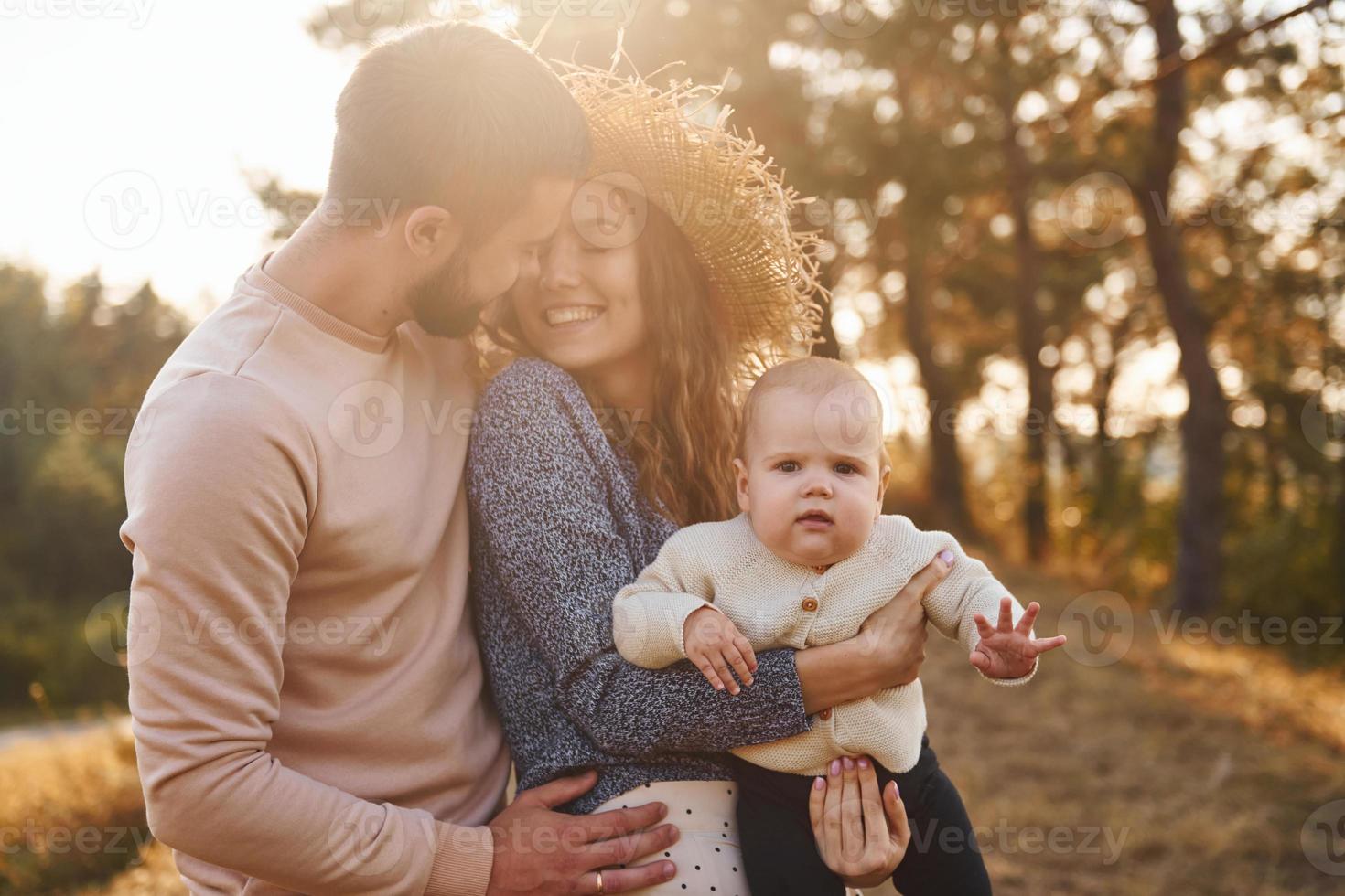 Happy family of mother, family and little baby rests outdoors. Beautiful sunny autumn nature photo