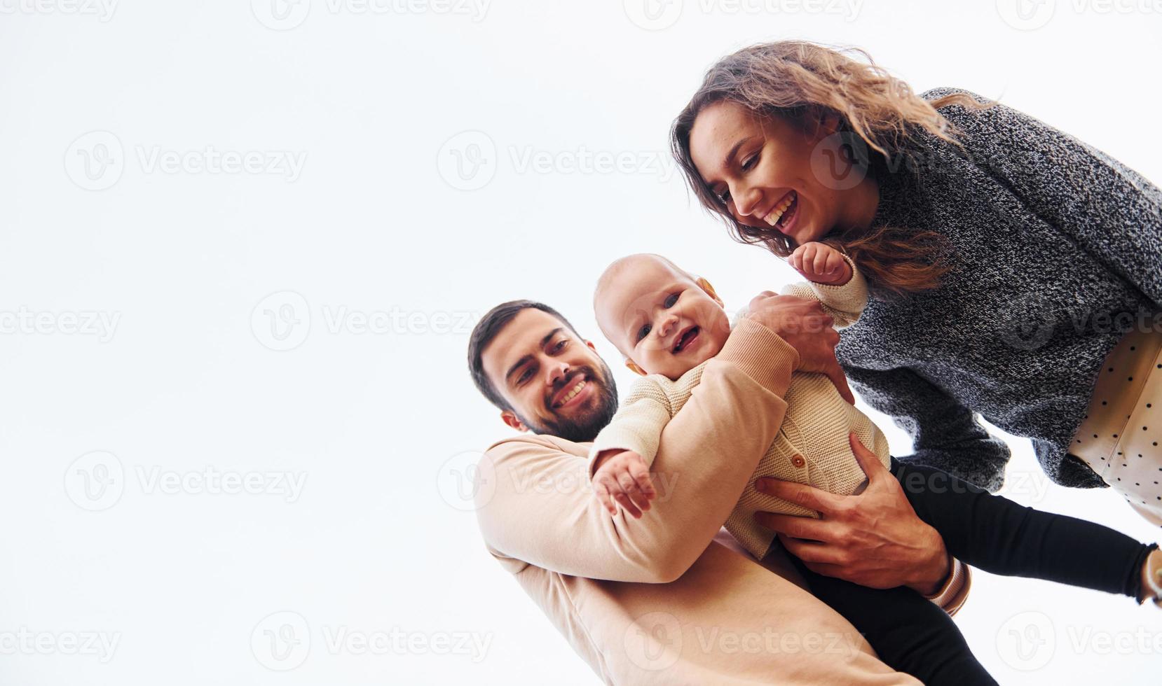 View from below. Happy family of mother, family and little baby rests outdoors. Beautiful sunny autumn nature photo