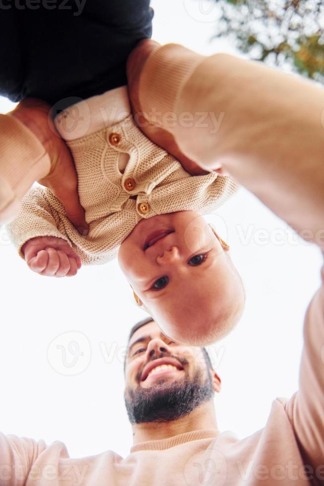 padre barbudo jugando con su hijo al aire libre durante el día soleado al aire libre foto