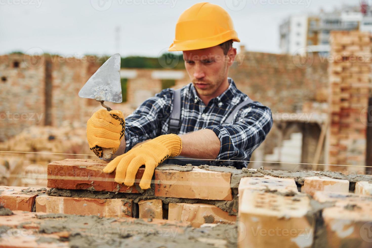 Laying bricks. Construction worker in uniform and safety equipment have job on building photo