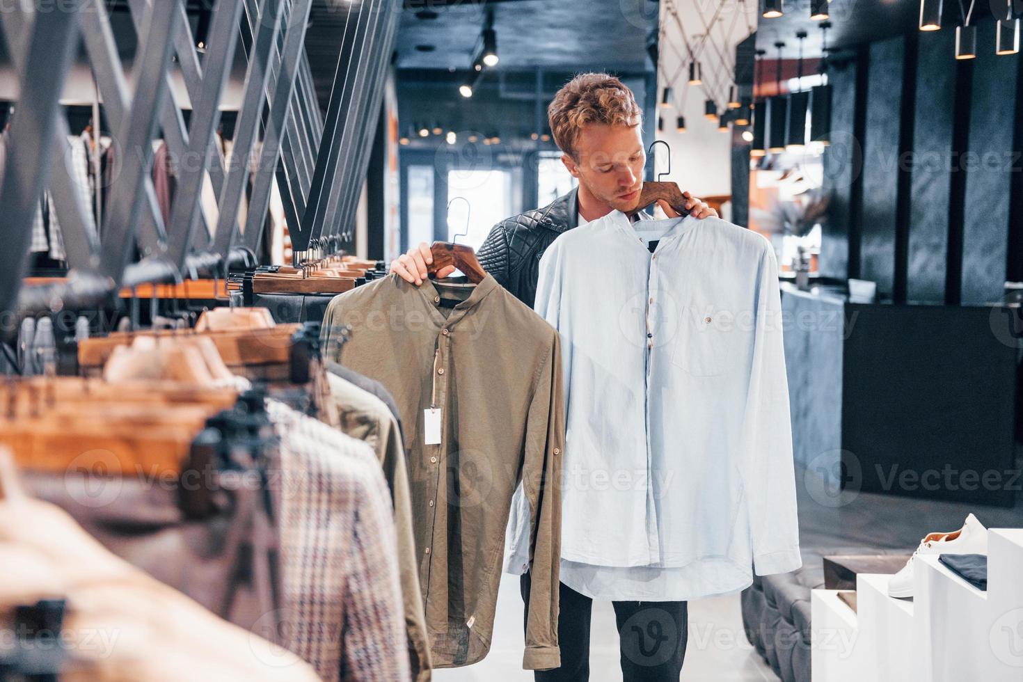 productos de calidad. chico joven en una tienda moderna con ropa nueva. ropa elegante y cara para hombres foto