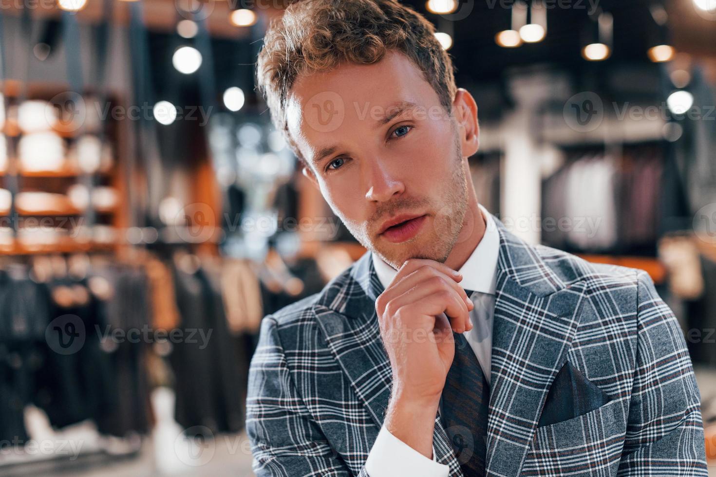 en chaqueta con corbata. chico joven en una tienda moderna con ropa nueva. ropa elegante y cara para hombres foto