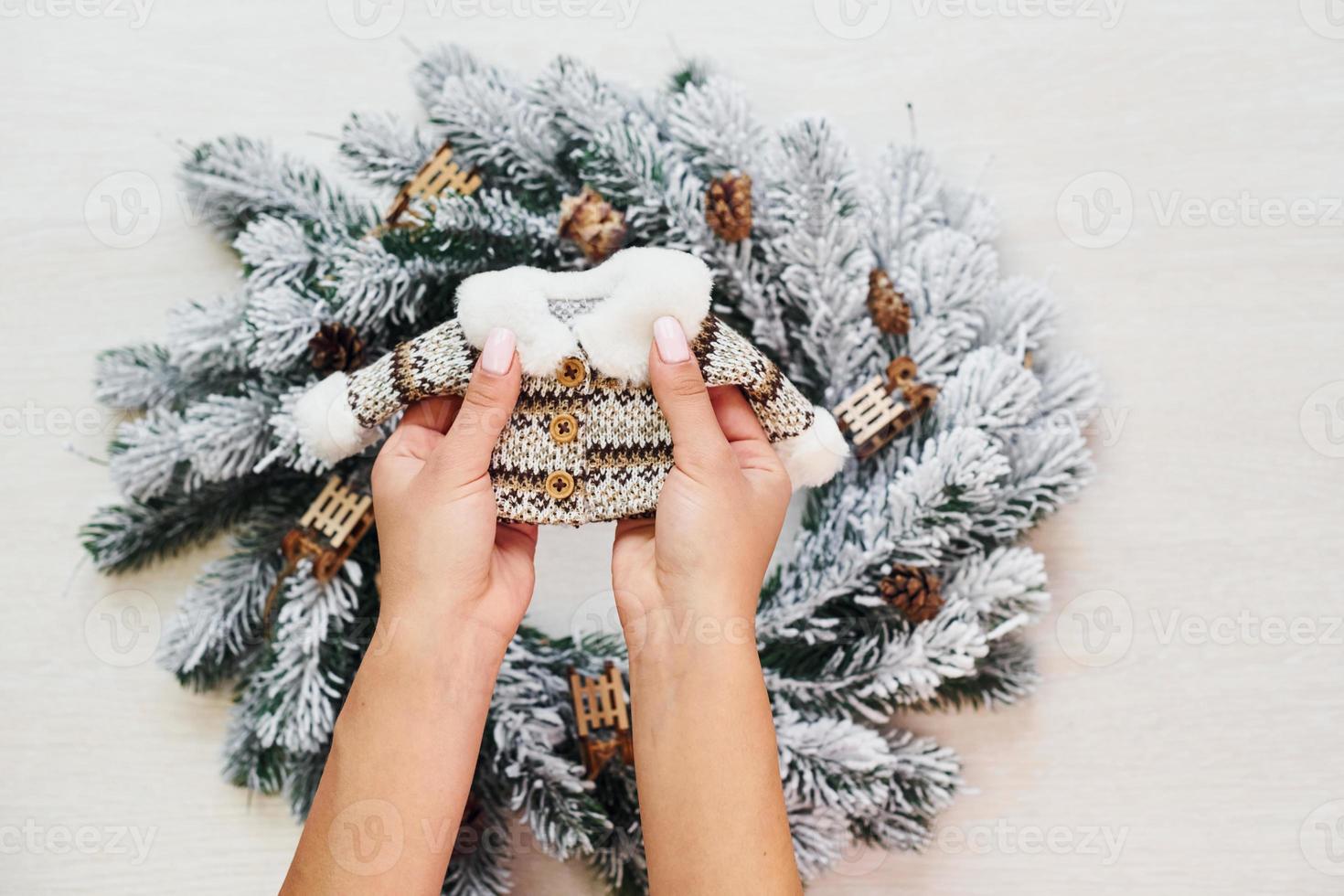 Woman's hands holds little sweater. Top view of christmas festive texture with new year decorations photo