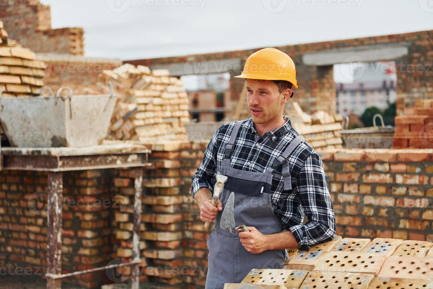 With spatula for construction. Worker in uniform and safety equipment have job on building photo